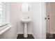 Elegant powder room with a pedestal sink, oval mirror, and dark wood-look floors for a modern touch at 17718 Terryglass Ln, Charlotte, NC 28278