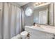 Well-lit bathroom with gray walls, vanity, mirror, octagonal window, and shower with gray curtain at 2014 Steeplechase Dr, Rock Hill, SC 29732