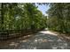 Gravel driveway cutting through trees along a wooden fence leading to a home at 202 Walden Ln, Weddington, NC 28104