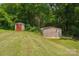 Two outbuildings on a grassy lawn surrounded by mature trees providing extra storage space at 327 Johnson Dairy Rd, Mooresville, NC 28115