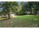 Expansive grassy backyard with shade trees, leading to a house and an outbuilding at 394 Link Dr, Iron Station, NC 28080