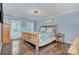 Primary bedroom boasts a rustic wooden bed frame, hardwood floors, and natural light from the double windows at 4831 Antioch Church Rd, Matthews, NC 28104