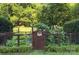 Wooden gate leading into a charming garden with lush greenery and mature trees at 4831 Antioch Church Rd, Matthews, NC 28104