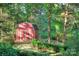 Red shed with white trim, nestled among trees and a stone pathway at 4831 Antioch Church Rd, Matthews, NC 28104