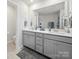 Bright bathroom featuring a double vanity with gray cabinets and a large mirror, offering a modern and functional space at 7032 Everly Commons Ln, Tega Cay, SC 29708