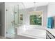 Bright bathroom featuring white tiled walls, a tub next to a large window, and glass shower at 1109 Sunnyview Cir, Matthews, NC 28105