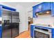 Modern kitchen with stainless steel refrigerator, blue cabinets, and access to other living spaces at 1109 Sunnyview Cir, Matthews, NC 28105
