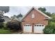 Red brick home featuring a two-car garage with white doors and mature landscaping at 1344 Moonshadow Ln, Shelby, NC 28150