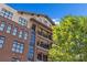 Beautiful building exterior featuring multiple floors, brick accents, balconies, and large windows, with a green tree nearby at 2312 Selwyn Ave # 502, Charlotte, NC 28207