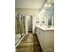 Modern bathroom with double sinks, a glass enclosed shower, and wood look floors at 243 Kerri Dawn Ln, Locust, NC 28097