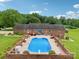 Aerial view of backyard pool area with brick fence, patio seating, landscaped lawn, and wooded area in background at 3381 Elaine Ave, Lincolnton, NC 28092
