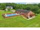 Aerial view of a brick home showcasing the backyard pool, patio, lush lawn and meticulous landscaping at 3381 Elaine Ave, Lincolnton, NC 28092