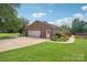 Detached brick garage featuring a spacious driveway, adjacent to lush landscaping and a serene pond at 3381 Elaine Ave, Lincolnton, NC 28092