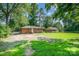Backyard featuring a well-maintained lawn, mature trees, and a charming home in the distance at 5323 Snow White Ln, Charlotte, NC 28213