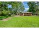 Picture of the backyard with grass, mature trees, and the back of a charming brick home at 5323 Snow White Ln, Charlotte, NC 28213
