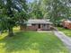A single-story brick home with a well-manicured lawn and mature trees at 5323 Snow White Ln, Charlotte, NC 28213