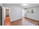 Bedroom with hardwood flooring, light gray walls, two windows, and open door to hallway and bathroom at 6513 Old Post Rd, Charlotte, NC 28212