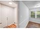 Hallway with laundry area, wood-look floors, leading to a room with a window at 6513 Old Post Rd, Charlotte, NC 28212