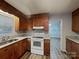 Functional kitchen with wood cabinets, granite countertops, white appliances, and a view into an adjacent living space at 6513 Old Post Rd, Charlotte, NC 28212