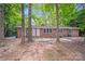 The rear exterior of a single-story brick house is nestled amongst tall trees and features two white entry doors at 6513 Old Post Rd, Charlotte, NC 28212