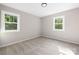 Bright bedroom featuring two windows, neutral paint, and plush carpet flooring at 7407 Limerick Dr, Charlotte, NC 28270