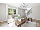 Sun-filled living room featuring wood floors, large windows, and stairs with iron railings at 7407 Limerick Dr, Charlotte, NC 28270