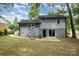 Exterior view of home with gray siding, brick foundation, and a large backyard at 8208 Doverdale Ln, Charlotte, NC 28217