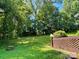 Large, lush backyard featuring green grass and mature trees with a brick retaining wall at 8417 Rolling Hills Ave, Hickory, NC 28602