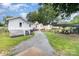 Backyard view featuring a gravel driveway, carport, and stairs to a porch, with lush greenery at 105 Mcgill Nw Ave, Concord, NC 28025