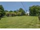 Expansive backyard with green grass, mature trees, and a wooden fence surrounding property at 1239 Mac Ln, Stanley, NC 28164