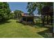 Outdoor storage shed on a lush green lawn featuring a wood pile and trailer at 1239 Mac Ln, Stanley, NC 28164