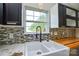 Farmhouse sink with black fixtures and multicolored backsplash under a window with a view at 1312 Shenandoah Cir, Rock Hill, SC 29730
