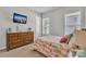 Bedroom has a floral pattern bedspread, a dresser and two bright windows with privacy shades at 1320 Torrens Dr, Wesley Chapel, NC 28110