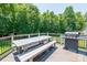 Open deck featuring a dining table, benches, grill, and wood flooring overlooking the backyard and green trees at 1320 Torrens Dr, Wesley Chapel, NC 28110
