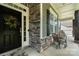 Inviting front porch with seating, a welcoming wreath, and stone accents at 1320 Torrens Dr, Wesley Chapel, NC 28110