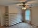 Open bedroom with neutral walls, carpeted floors, shelving, and a ceiling fan with lighting at 1519 Midland Dr, Hudson, NC 28658