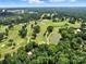 Wide aerial view of a golf course with tree-lined fairways, pond, and surrounding community at 2104 Stoneyridge Dr, Charlotte, NC 28214