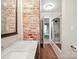 Modern bathroom featuring marble countertops, walk-in shower and brick accent wall at 2104 Stoneyridge Dr, Charlotte, NC 28214