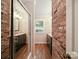 Hall bathroom featuring duel vanities, brick accent wall and wood flooring at 2104 Stoneyridge Dr, Charlotte, NC 28214