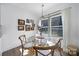 Cozy dining area with a glass table, four chairs, decorative paintings, and natural light from a large window at 333 Anne Ave, Waxhaw, NC 28173