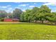 Expansive green backyard with a storage shed and view of the main house through the trees at 36433 Azalea Cir, New London, NC 28127