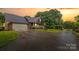 Beautiful brick house with a two-car garage and porch bathed in the warm glow of sunset at 36433 Azalea Cir, New London, NC 28127