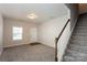 Cozy living room featuring neutral walls, plush carpet, a white door, and staircase at 437 Danielle Way, Fort Mill, SC 29715