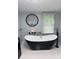 Elegant black and white bathtub with modern fixtures, complemented by a tree art piece and soft lighting at 6490 Alta Ctr, Denver, NC 28037