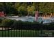 Community pool featuring lounge chairs and umbrellas, surrounded by lush greenery and a black metal fence at 8524 Loxton Cir, Charlotte, NC 28214