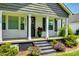 A covered front porch with black shutters, columns, colorful flowerbeds, and black steps enhance the entry at 903 Rhode Island Ave, Kannapolis, NC 28083