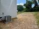 View of the side of the home showing the A/C unit and an undeveloped area of the backyard at 907 W Georgia Ave, Bessemer City, NC 28016
