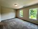 Comfortable bedroom with neutral walls, plush carpet, and natural light from the two windows at 907 W Georgia Ave, Bessemer City, NC 28016