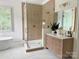 Bright bathroom with a glass-enclosed shower, soaking tub, and a modern vanity with gold fixtures at 9604 Oliver Ct, Harrisburg, NC 28075