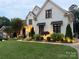 Elegant white brick home featuring black window frames, awnings, and lush landscaping with pathway lights at 9604 Oliver Ct, Harrisburg, NC 28075